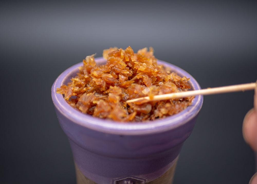 Shisha tobacco being packed in a hookah bowl 1024x1024